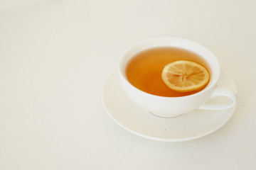 Black tea with lemon in a white cup on a white table and background.