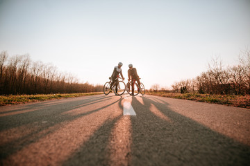 Fototapeta premium Two caucasian middle-aged cyclists stand on the road