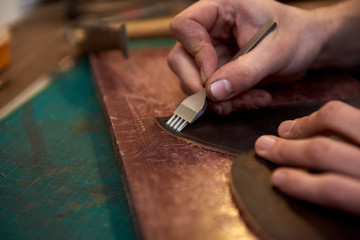 Close up of leather master hands working with natural leather and craft tools. Leather and the craft tools.