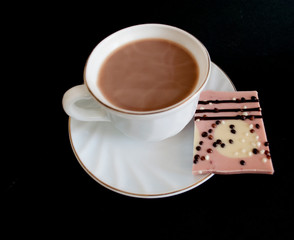on a dark background a cup of cocoa and a bar of chocolate