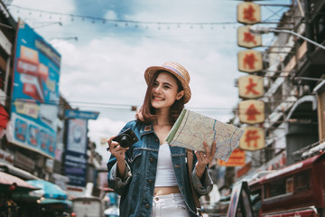 Young beautiful Asian backpack traveler woman using camera and smile. Asia summer tourism concept