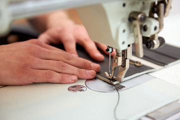 Closeup leathermaker hands stitching a wallet in sewing machine. Working process of leather craftsman.