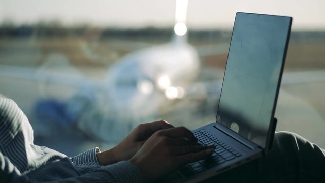 Laptop and woman's hands typing on it at the airport