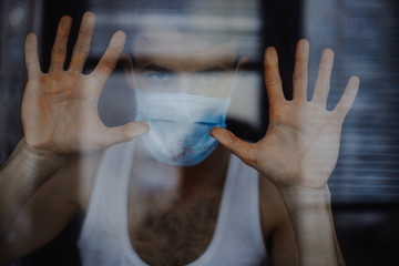portrait of a young man wearing a protective medical mask and quarantining at home. The concept of...