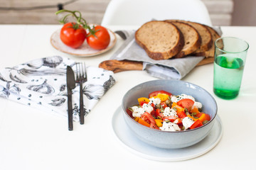 Salad bowl with chopped tomatoes, pepper, cream cheese, black sesame and pumpkin seeds