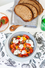 Salad bowl with chopped tomatoes, pepper, cream cheese, black sesame and pumpkin seeds