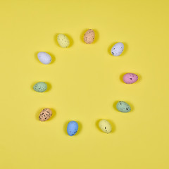 Easter eggs laid out in a circle on a yellow background. View from above.