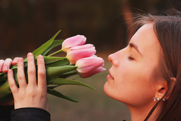 Beautiful girl sniffs flowers. Girl and tulips. Spring