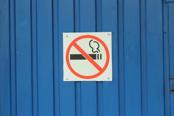 On the blue wall there is a white sign with an inscription prohibiting smoking. The concept of...