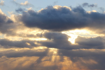Obraz premium The sun at sunset or dawn behind the clouds, shines through. The sun's rays in the sky