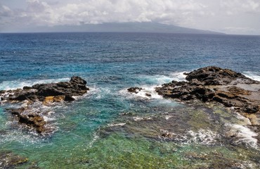 From the shores of the islet of Djeu, the island of Brava sits at sea in the horizon under the clouds