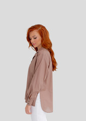 Young beautiful red-haired girl in a light shirt in the color of moko.