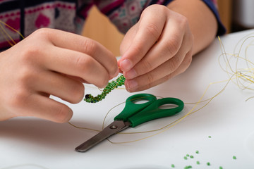 Children hands make bead and wire jewelry