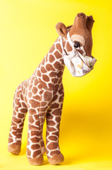 Toy giraffe in a madical mask on a yellow background. Coronavirus
