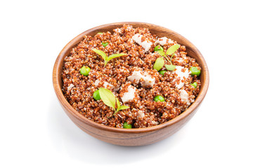 Quinoa porridge with green pea and chicken in wooden bowl isolated on a white background. Side view.