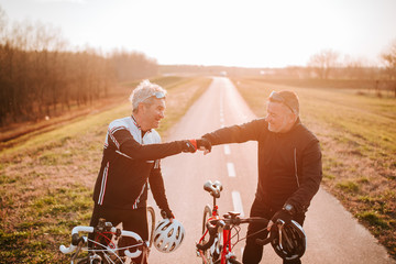  Two caucasian middle-aged cyclists stand on the road