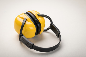 Yellow headphones on a light background: the concept of hearing protection and personal health and safety equipment
