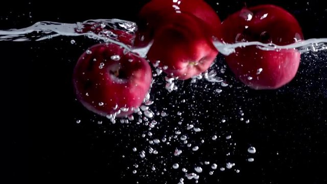 The apple falls into the black water until the sponge splits beautifully on the black background.