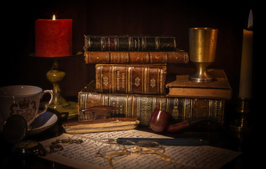 An old desk with a pile of vintage brown leather books, an open book with eye glasses, a cup of coffee, a red candle with flame, a vintage pocket clock, earth globe. - obrazy, fototapety, plakaty