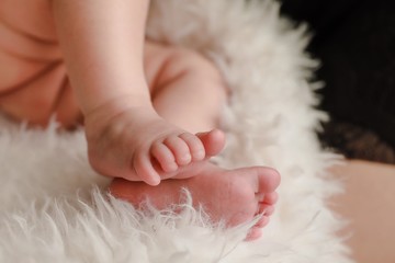 Cute baby feet on a fluffy cream blanket