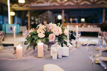 Obraz na płótnie Canvas Tenderly decorated wedding table with flowers, glasses and candles in candlesticks