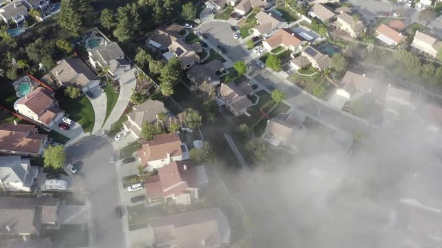 Aerial birds eye over morning fog of neighborhood homes