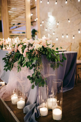 Romantic wedding table of newlyweds decorated with a blue tablecloth, candles, flowers in the style of rustic