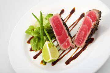 Medium grilled tuna steak with vegetables isolated on white background