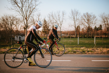 Fototapeta premium Two middle-aged men ride a bicycle on a road