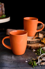 Two beautiful large orange cups for tea and drinks in a beautiful composition.