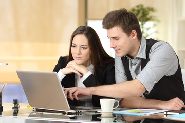 Coworkers working together checking laptop content