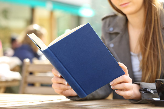 Young woman reading book on a cafe terrace