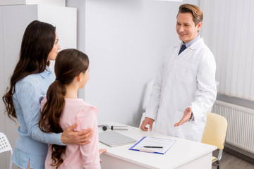 Obraz premium smiling ent physician looking and welcoming mother and daughter