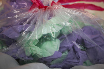 close-up on a transparent trash bag with purple and green tissues to recycle