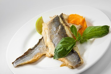 Appetizing grilled seabass fish with vegetables isolated on white background