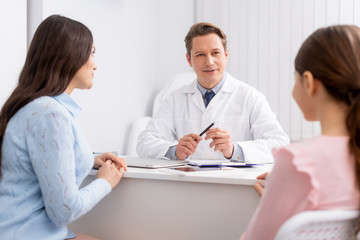 selective focus of mother and daughter on consultation with ent physician