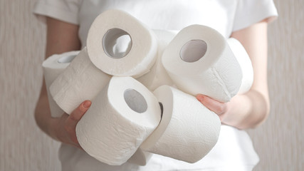 Woman holds many rolls of toilet paper representing panic buying during the coronavirus COVID-19 pandemic in 2020. preparation for quarantine and economic crisis due to coronavirus. Hygiene concept