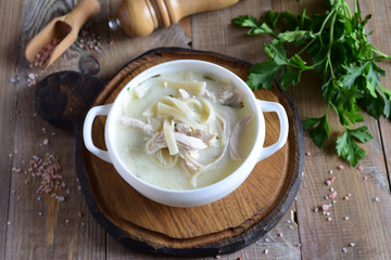 Hot soup with noodles and meat in a beautiful white plate on a wooden table