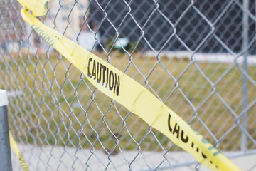yellow caution tape on metal chain link fence