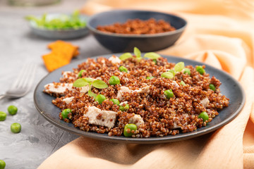 Quinoa porridge with green pea and chicken on ceramic plate on a gray concrete background. Side view, selective focus.