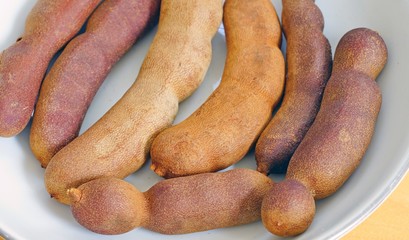 A bowl of fresh tamarind fruit pods
