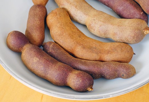 A bowl of fresh tamarind fruit pods