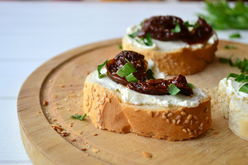 French baguette with cream cheese and dried tomatoes on a white background.