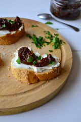 French baguette with cream cheese and dried tomatoes on a white background.