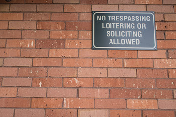 Fototapeta na wymiar No trespassing or loitering sign on brick building