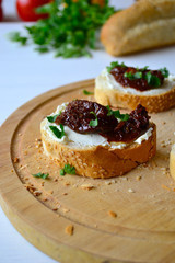 French baguette with cream cheese and dried tomatoes on a white background.