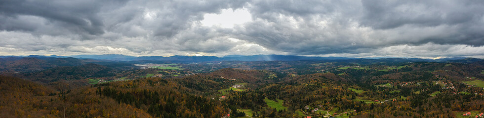 Panorama of notranjska region of slovenia in autumn colors, with dense clouds carrying storm approaching. Beautiful autumn weather viewed from Ulovka, visible mount Sneznik and Javornik.