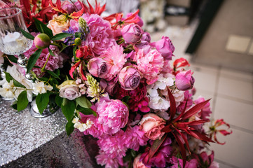Composition of pink, violet, white flowers is on the table covered with silver tablecloth