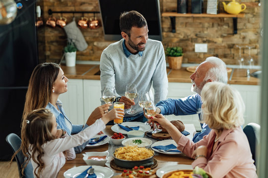 Happy multi-generation family toasting while having lunch together at home. - Powered by Adobe