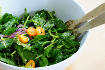 Fresh green kale salad with sliced kumquat fruit in a bowl